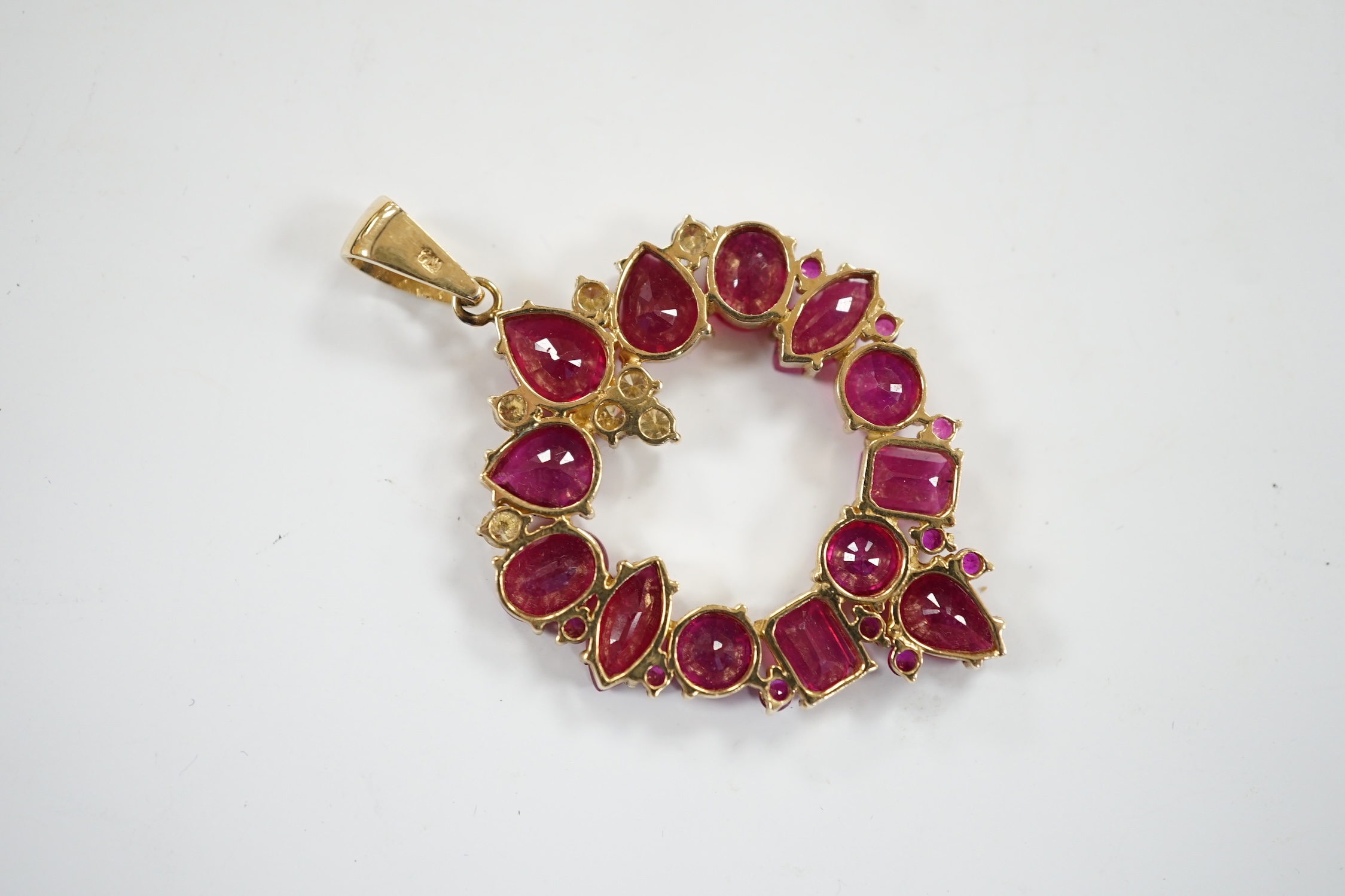 A modern 14k, ruby(treated) and diamond cluster set open work pendant, overall 52mm, gross weight 10.9 grams.